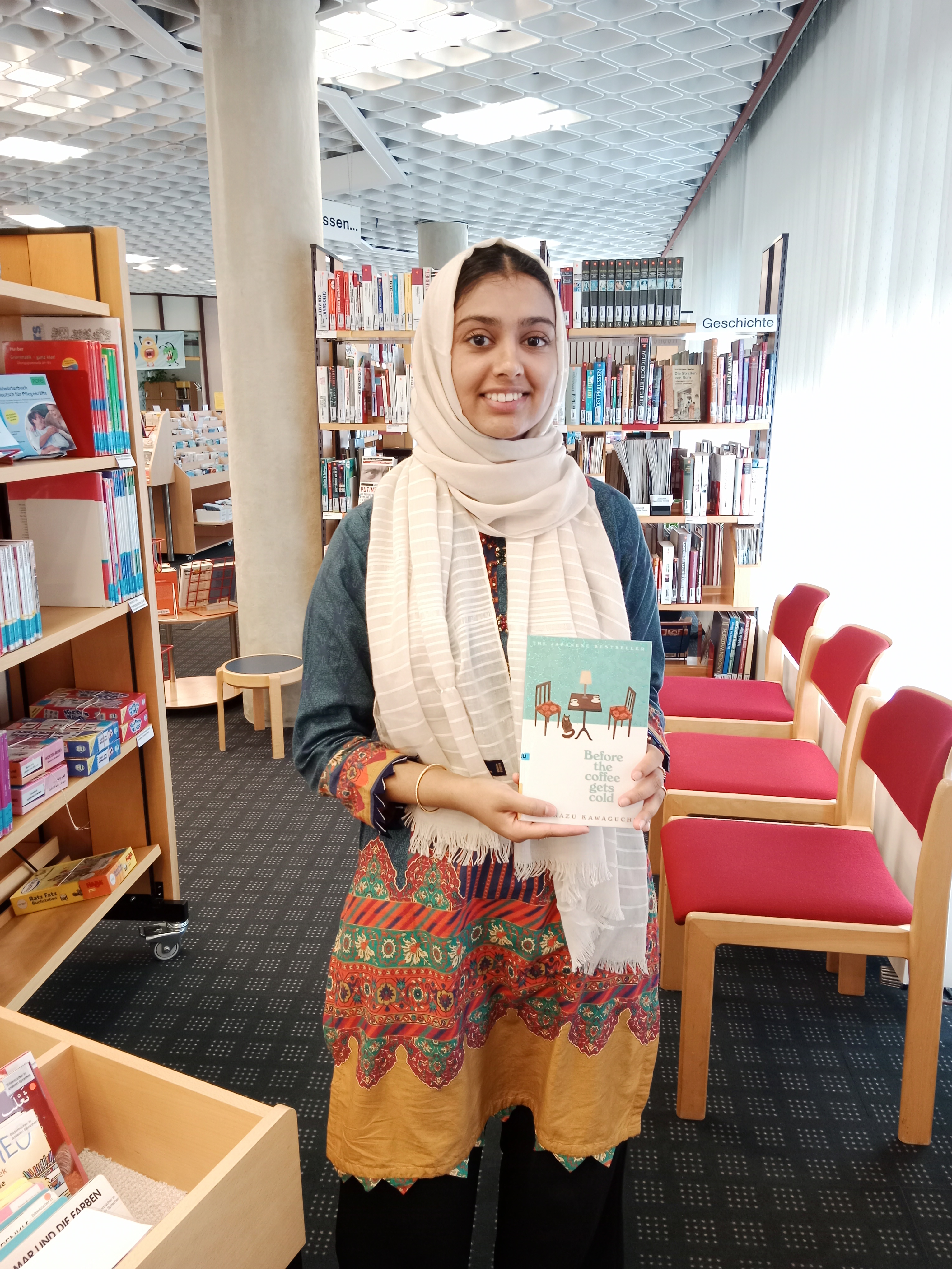 Khadija Mehmood hält das Buch "Before the coffee gets cold" hoch